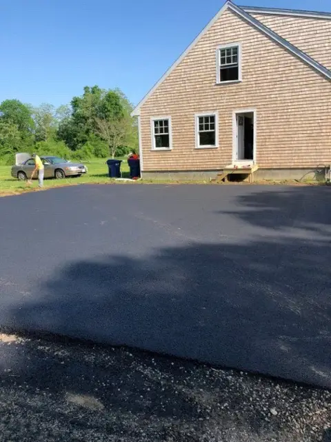 Fresh asphalt beside a shingled house