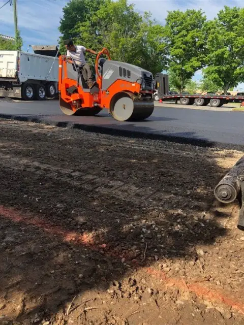Roller working behind a dump truck
