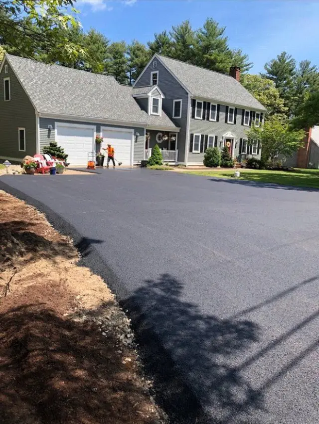 New black asphalt driveway in front of a colonial home