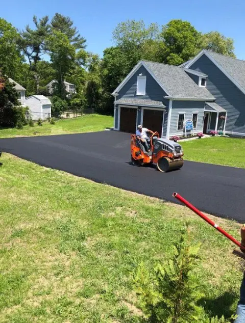 Small roller on a driveway next to a blue house